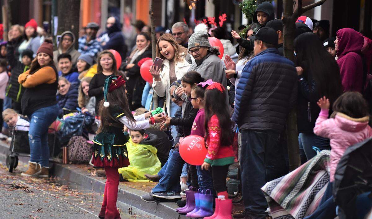 One of the members of the Another Way Recovery and Resource Center parade participants hands out a gift to a girl in the crowd during the Merced Christmas Parade on Saturday, Dec. 3, 2022.