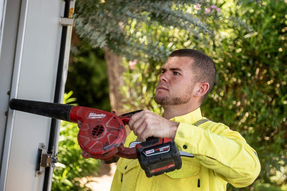 Tanner Harkreader, 28, a lead lighting technician with the City of Merced, performs routine maintenance on a traffic signal cabinet at the intersection of Olive and Parsons avenues in Merced, Calif., on Thursday, July 31, 2025. 