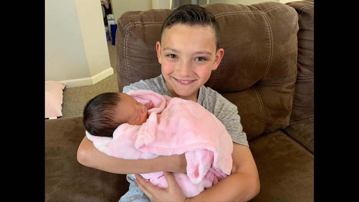 Eight-year-old Rivera Elementary second grader Tyson Sanchez, holds his newborn sister, Scarlett Gaeta, days after he helped his mother through pregnancy complications on April 11, 2019, with efforts that his school staff are calling heroic, according to the Merced City School District.