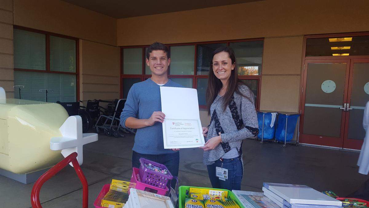 Lucca Lorenzi is presented with a certificate of appreciation by Caitlin Burns, who is community relations assistant at Lucile Packard Children's Hospital Stanford, after Lorenzi donated art supplies to the hospital last fall.