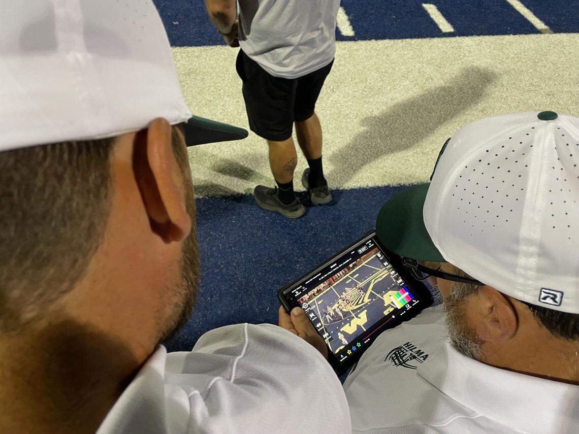 Hilmar High assistant football coach watch video replays on a tablet during a football game against Atwater High on Sept. 13 at Dave Honey Stadium.