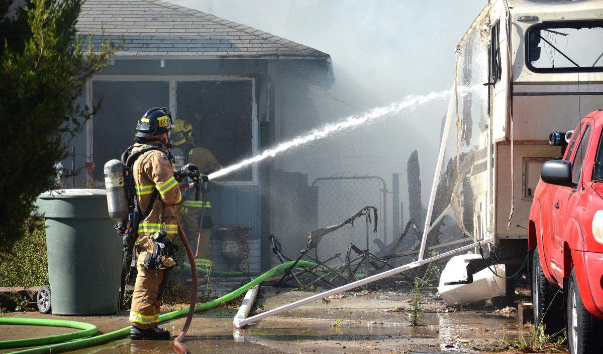 Firefighters battle a large fire that caused explosions and damaged two homes Tuesday, July 23, 2019, at the corner of Shirley Street and Dawn Avenue in Merced.