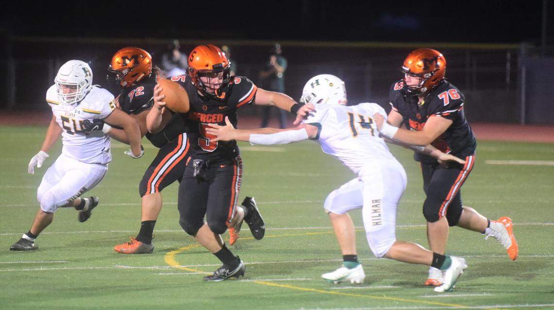 Merced High quarterback Seth Scheidt (5) tries to avoid the tackle of Hilmar’s Nick Vitorino during the Bears’ 14-13 win on Friday, April 2, 2021 at Veteran Stadium in Merced, Calif.