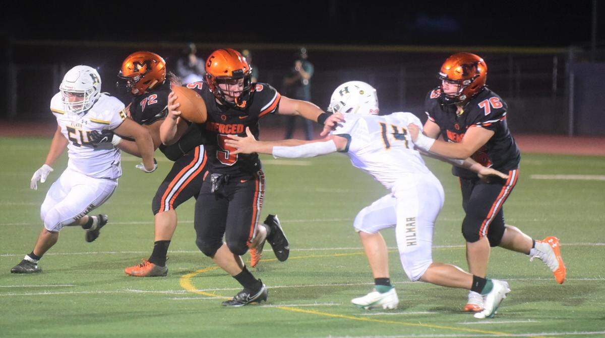 Merced High quarterback Seth Scheidt (5) tries to avoid the tackle of Hilmar’s Nick Vitorino during the Bears’ 14-13 win on Friday, April 2, 2021 at Veteran Stadium in Merced, Calif.