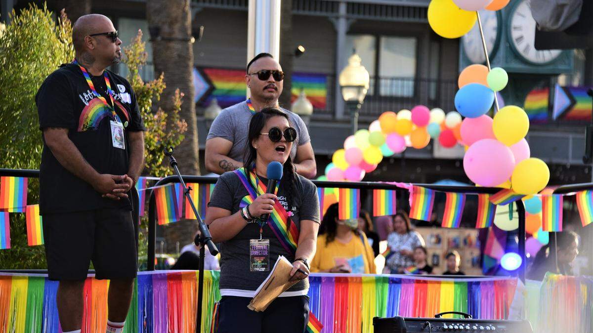 A woman stands on a stage decorated with rainbows.
