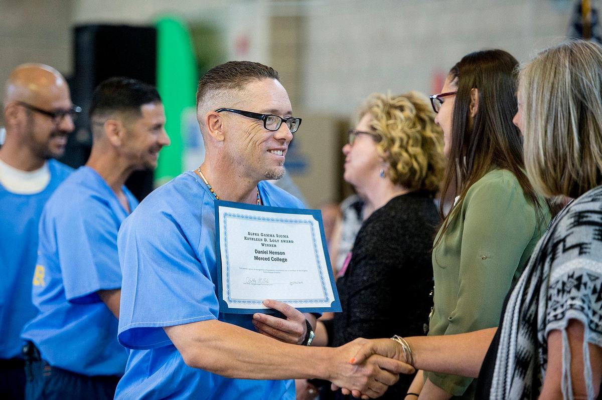 Inmate Daniel Henson, 37, left, shakes hands with Merced College professor Jennifer McBride after being recognized for receiving the Alpha Gamma Sigma Kathleen D. Loly award during a graduation ceremony at Valley State Prison in Chowchilla, Calif., on Wednesday, May 1, 2019. The ceremony recognized more than 60 inmates for their educational achievements including Associate of Arts degrees, high school diplomas, General Education Development certifications and those who have completed Career Technical Education programs.