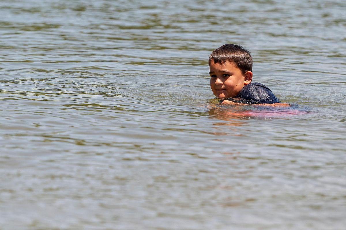 Grayson Aguilar, 6, of Atwater, searches for items on the lake bed while cooling off on Thursday, July 8, 2021.