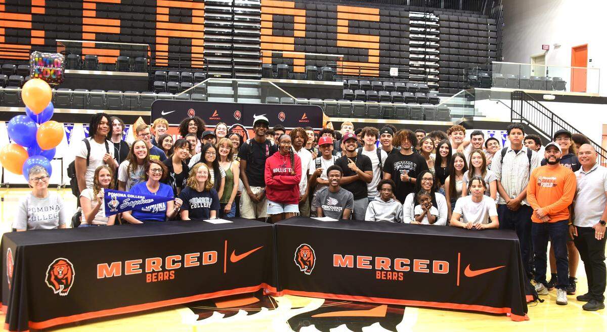 The Merced High School track team stands behind seniors Donovan Marshall and Elsa Van Dyke (center) after the two signed their national letter of intent to compete at four-year colleges on Tuesday, May 28, 2024.