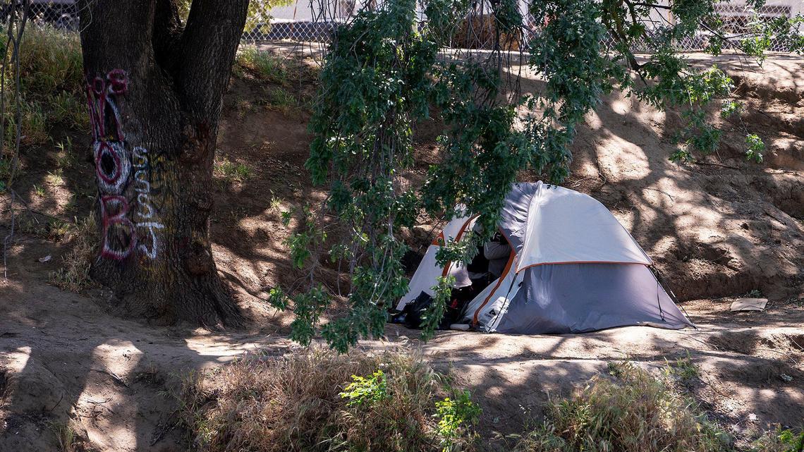 A person moves around inside a tent located at a small encampment along the bank of Bear Creek in Merced, Calif., on Tuesday, April 12, 2022.