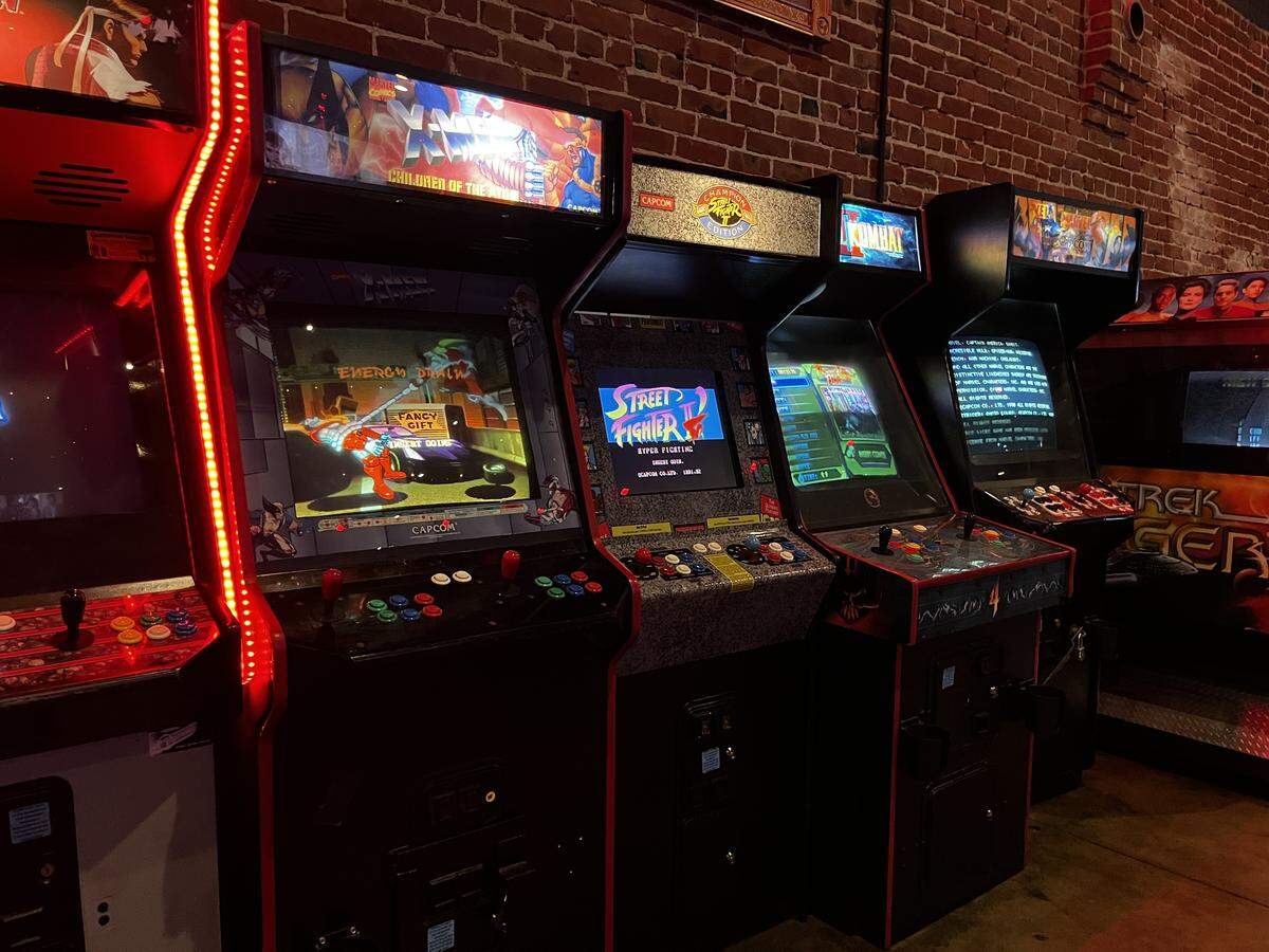 Old-school arcade games with flashing screens against a brick wall background.