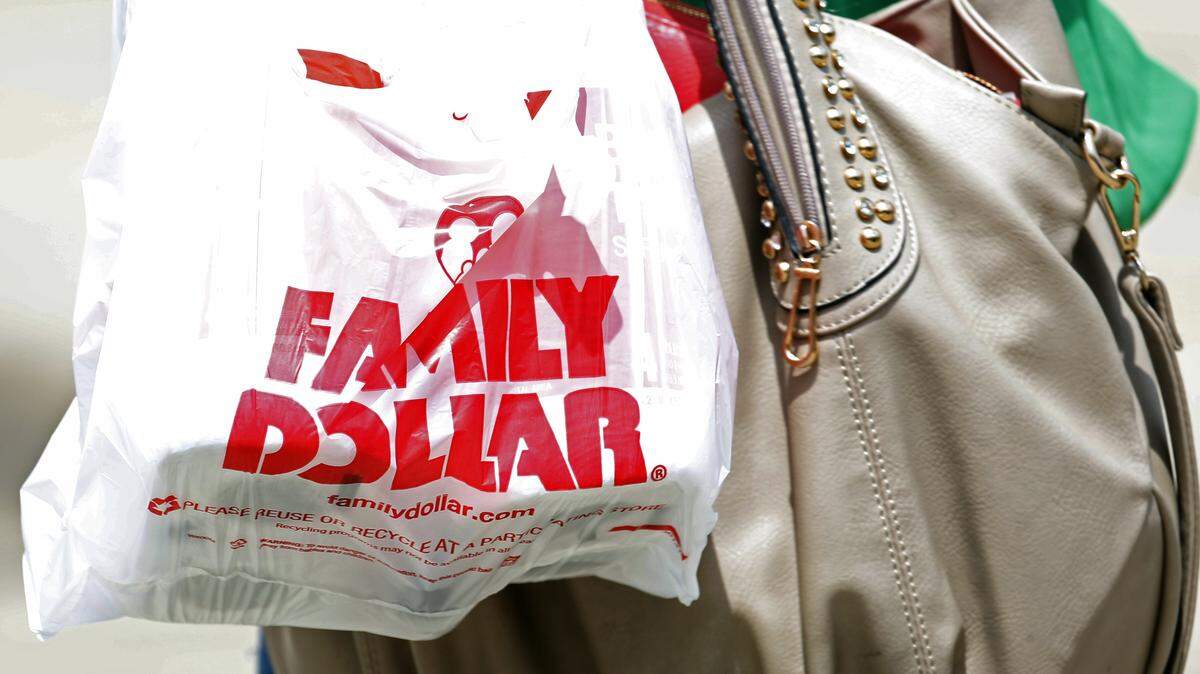 In this Aug. 19, 2014 photo, a customer carries out her purchases from a Family Dollar store in Jackson, Miss. Family Dollar on Friday, Sept. 5, 2014 rejected Dollar General’s latest acquisition offer, and Dollar Tree says it will now divest as many stores as needed to get antitrust clearance for its deal to buy Family Dollar. (AP Photo/Rogelio V. Solis)
