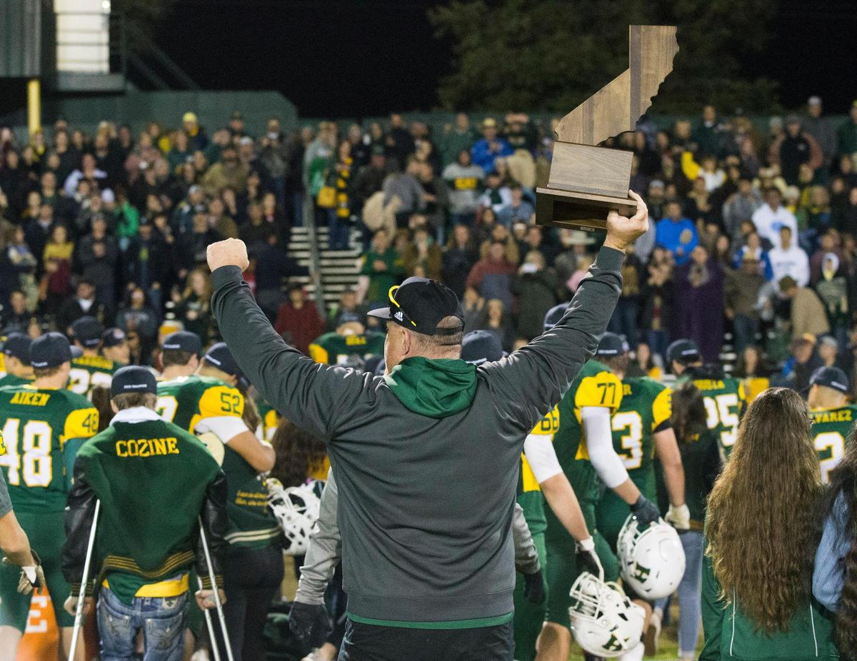 Hilmar High football coach Brad Mason holds up the state championship trophy after Hilmar beat Strathmore High during the CIF State 6-AA High School Football State Championships at Hilmar High Saturday Dec. 15, 2018.
