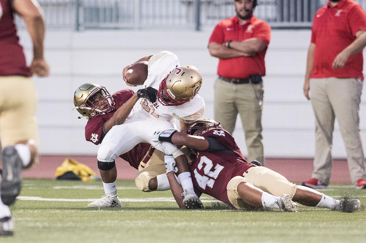 Golden Valley juniors Avery Townsel (21) and Gerardo Alvarado (42) tackle Centennial sophomore Anthony Glass (21) during a game at Veterans Stadium on the campus of Golden Valley High School in Merced, Calif., on Friday, Aug. 31, 2018. The Golden Hawks beat the Cougars 38-15.