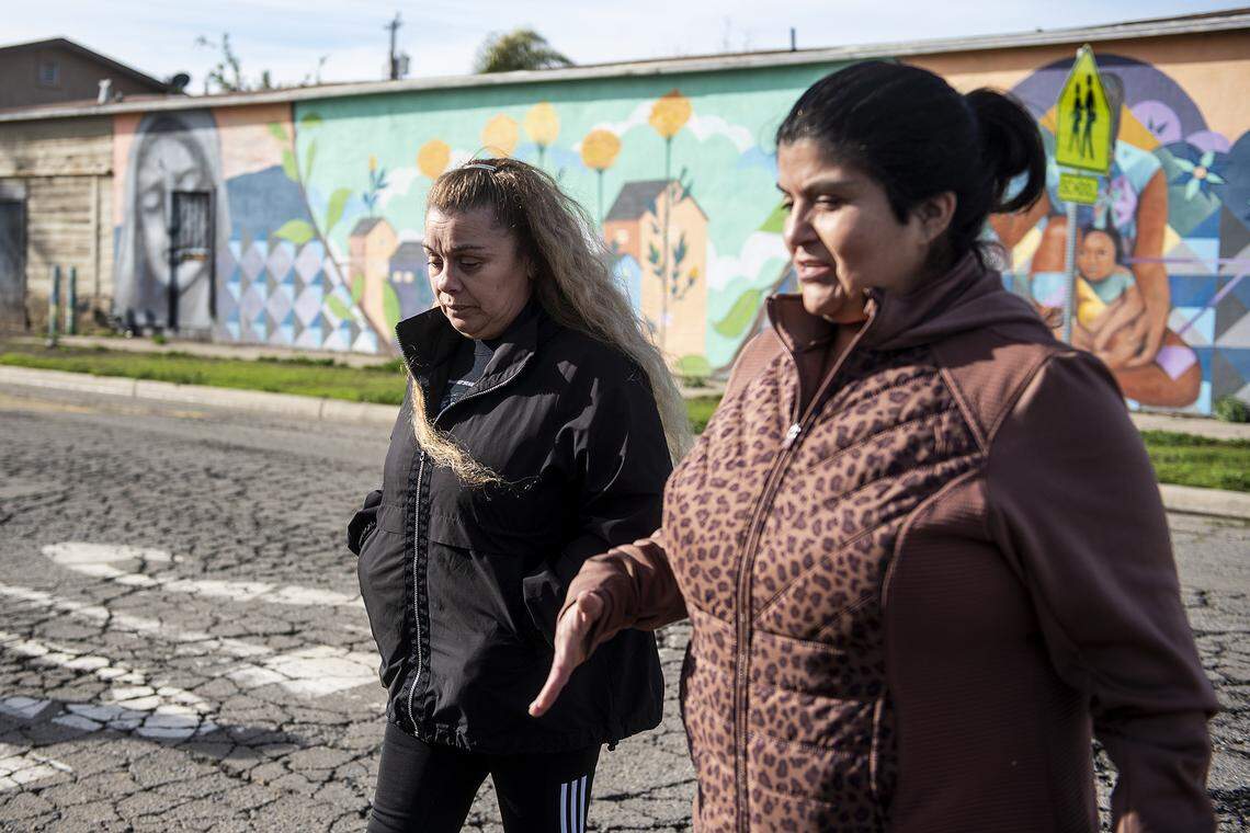 Alicia Rodriguez, president of St. Vincent De Paul Planada Sacred Heart Conference, right, speaks with Gloria Canal, left, as they walk to the home of Canal’s father in Planada, Calif., on Thursday, Jan. 12, 2023. Canal helped her father evacuate from the town after flooding forced residents from their homes.