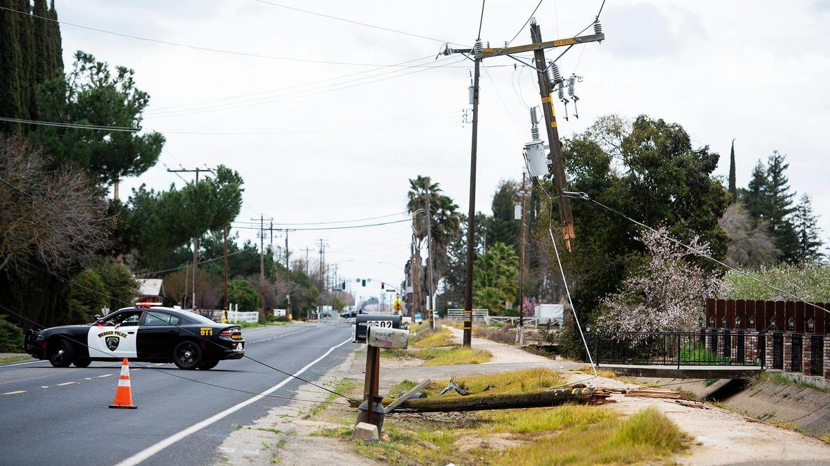 Merced police officers and firefighters respond to the scene of a solo-vehicle crash that severed a power pole and left a vehicle in a canal along East Childs Avenue in Merced, Calif., on Sunday, March 1, 2020. According to Merced Fire Battalion Chief Mickey Brunelli, the road is closed in the area as Pacific Gas and Electric Company work to restore power and remove power lines from the roadway.