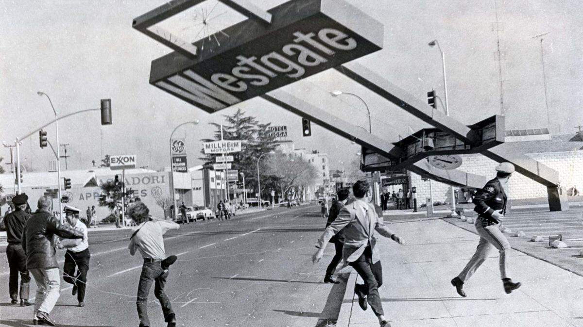 This picture shows the Westgate Shopping Center sign falling a few minutes after cutting torches were used to slice into supporting posts and workers pulled the sign over to remove the danger to motorists and pedestrians at West 17th and R streets. Winds estimated at 25 to 30 miles per hour had damaged seams in support posts before the sign was pulled over on February 24, 1973. This photo was published on February 26, 1973.