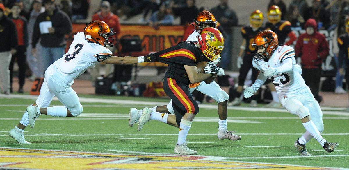 Oakdale running back, Leo Ayala, center is grabbed from behind by Merced defensive back, Quincey Collins in the fourth quarter Friday night, Nov. 22, 2019 in Oakdale.