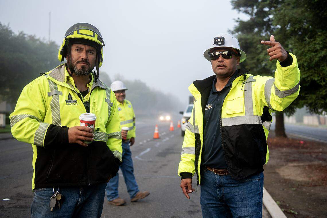 City of Merced Arborist and Public Works Director for Parks and Trees Division, Angel Nunez, 46, right, speaks with Tree Division Lead Cain Macias, left, as crews work to remove selected trees from the median along West Olive Avenue in Merced, Calif., on Thursday, Nov. 6, 2025. 
