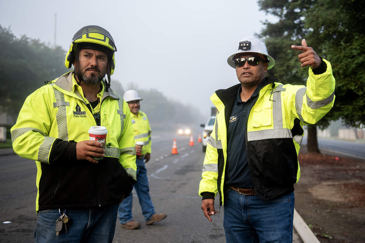 City of Merced Arborist and Public Works Director for Parks and Trees Division, Angel Nunez, 46, right, speaks with Tree Division Lead Cain Macias, left, as crews work to remove selected trees from the median along West Olive Avenue in Merced, Calif., on Thursday, Nov. 6, 2025.