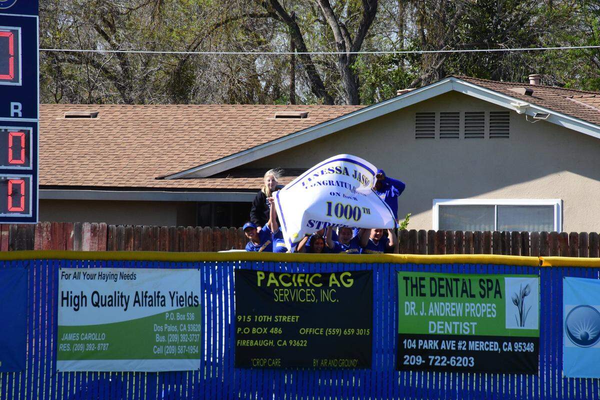 The Dos Palos High junior varsity softball team holds up a sign over the center field fence to congratulate Broncos senior Janessa Jasso on her 1,000th career strikeout on Tuesday afternoon at Dos Palos High in Dos Palos, Calif.