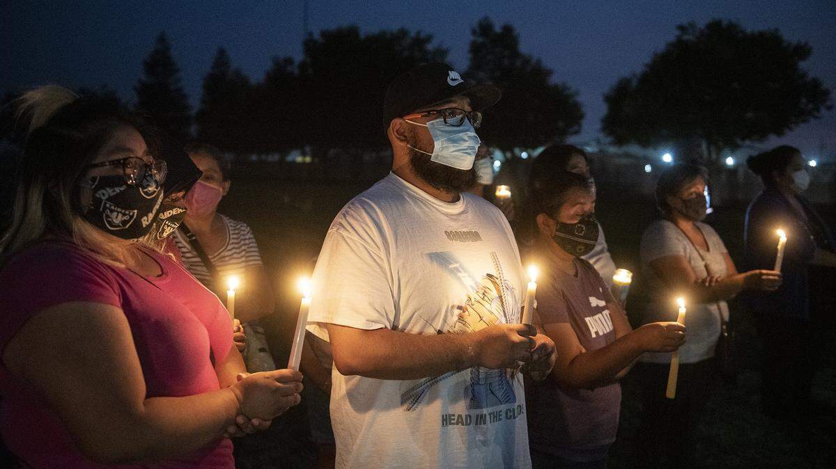 Foster Farms employee Kevin Vera, 28, of Livingston, center, attends a community candlelight vigil with family members at the Max Foster Sports Complex in Livingston, Calif., on Thursday, Sept. 3, 2020. The vigil was held to honor the eight lives lost and hundreds of families impacted by a COVID-19 outbreak at Foster Farms’ Livingston plant.