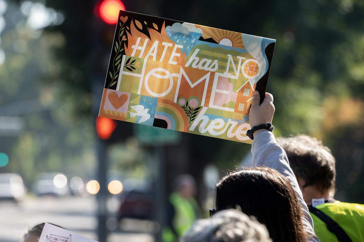 Protesters walk along M Street while holding signs during a “No Kings” protest in Merced, Calif., on Saturday, Oct. 18, 2025. 