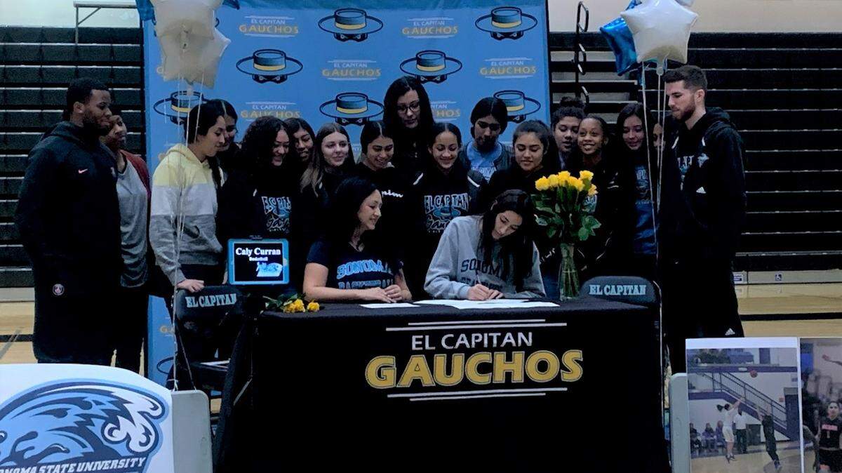 El Capitan High senior Caly Curran is joined by her mother, Jovita Alvarez, and her Gauchos teammates and coaches as she signs her national letter of intent to play basketball at Sonoma State University on Friday at El Capitan High School.