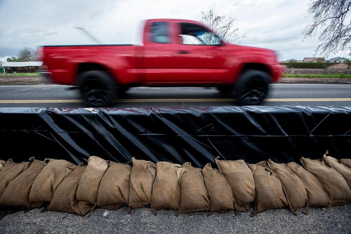 Sandbags and a retaining wall line a section of West North Bear Creek Drive in Merced, Calif., on Tuesday, March 14, 2023.