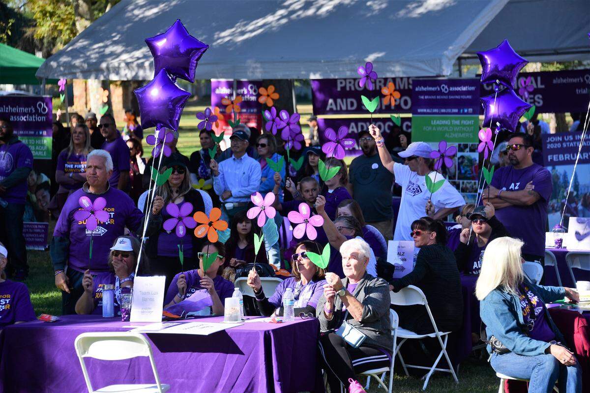 The crowd holds up their different colored flowers during a ceremony at the sixth annual Walk to End Alzheimer’s at Applegate Park in Merced on Saturday, Oct. 5, 2019.