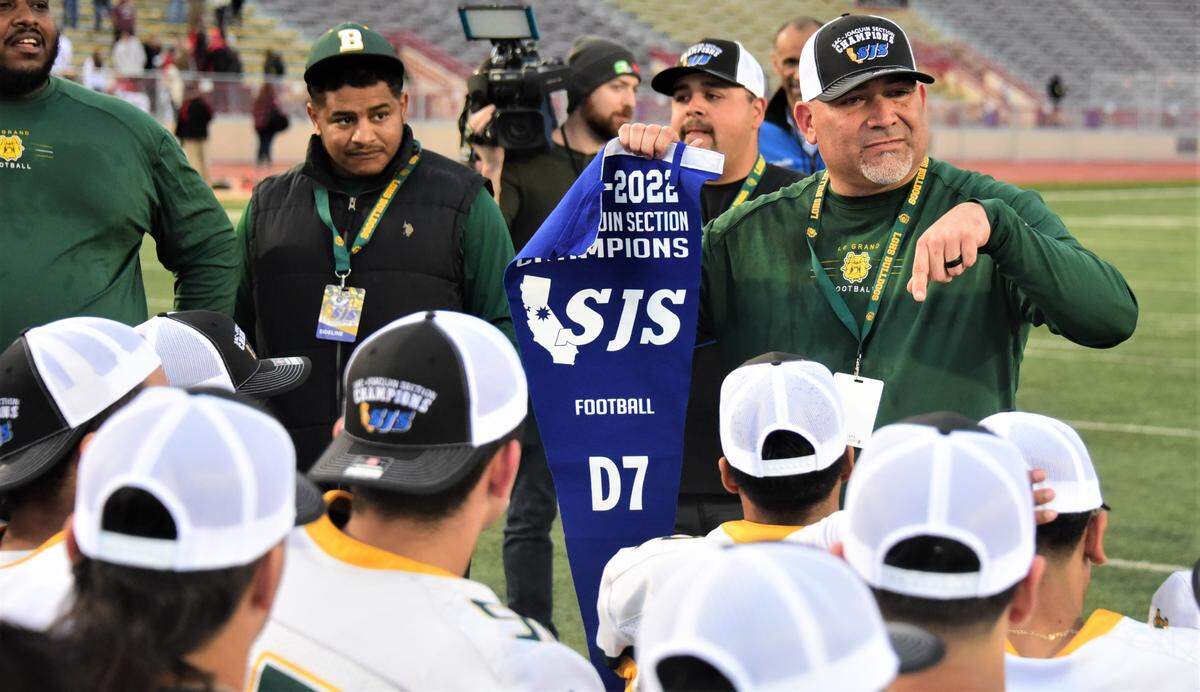 Le Grand High coach Aaron Martinez shows off the Sac-Joaquin Section Division VII championship banner to his players after the Bulldogs defeated Woodland Christian 35-12 on Friday, Nov. 26, 2021 at Sacramento City College’s Hughes Stadium.