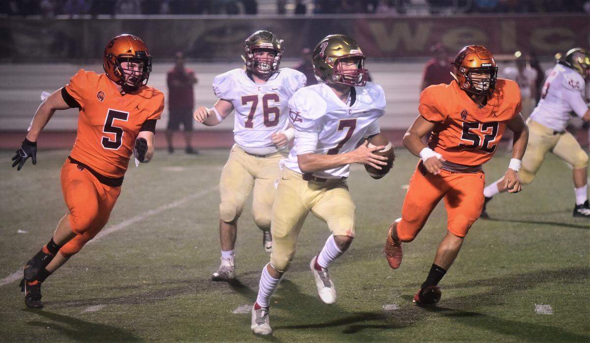 Golden Valley quarterback Eleazar Garza (7) scrambles to avoid Merced defenders Seth Scheidt (5) and Jalonn Booth (52) during a game on Friday, Oct. 29, 2021 at Veterans Stadium in Merced, Calif.