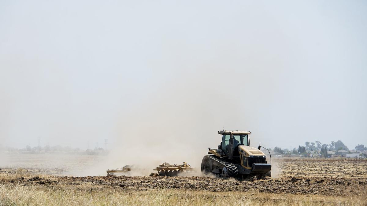 Farm equipment sends dust into the air on a farmland near West Bellevue Road in Merced, Calif., on Tuesday, July 3, 2018.