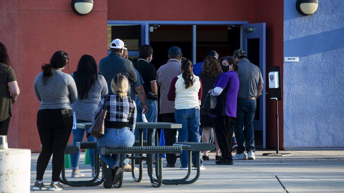 People line up to receive a COVID-19 vaccine outside of vaccination clinic inside the Cesar E. Chavez Middle School gymnasium in Planada, Calif., on Thursday, March 4, 2021.