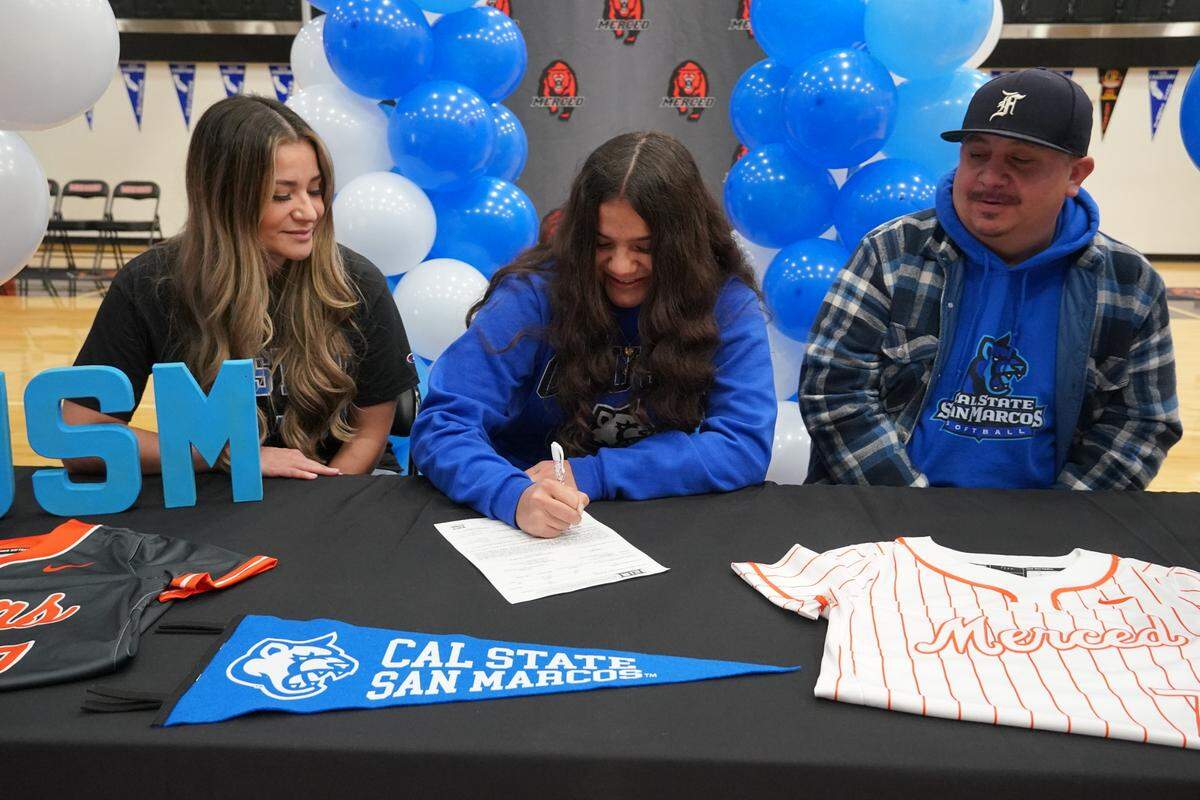 Merced High senior Ellie Alvarez signs her national letter of intent to accept a softball scholarship to Cal State San Marcos as her mother Tania Solis and father Rene Alvarez look on during a ceremony at Merced High School on Wednesday, Feb. 2, 2022.