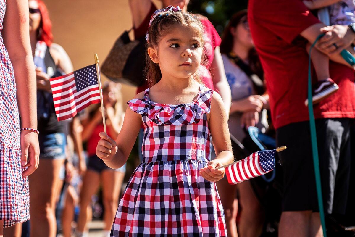 Faith Gurrola, 5, of Atwater, waves American flags while watching floats pass by during a Fourth of July parade in Atwater, Calif., on Monday, July 4, 2022.