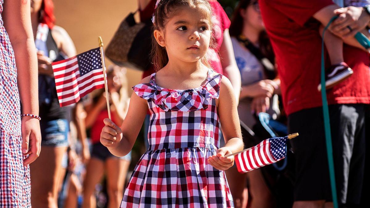 Faith Gurrola, 5, of Atwater, waves American flags while watching floats pass by during a Fourth of July parade in Atwater, Calif., on Monday, July 4, 2022.