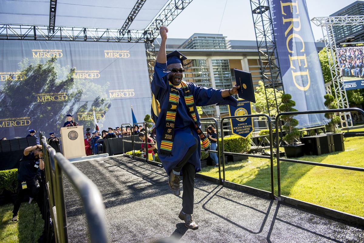 Auguste Kouadio, 50, of the Ivory Coast, celebrates as he dances down the ramp after graduating with his master's degree in interdisciplinary humanities during the University of California, Merced School of Social Sciences, Humanities and Arts spring commencement in the Carol Tomlinson-Keasey Quad on the UC Merced campus in Merced, Calif., on Saturday, May 12, 2018.