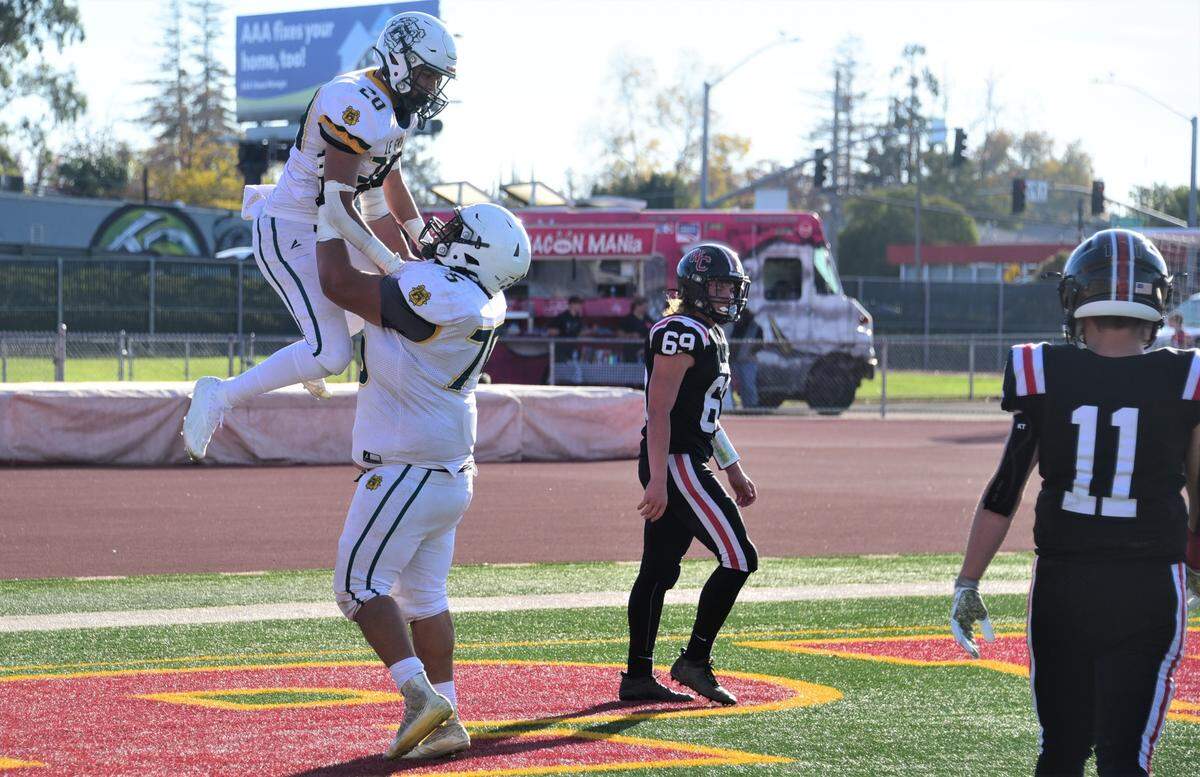 Le Grand High lineman Fermin Villegas (75) lifts up sophomore receiver Reyes Diaz after Diaz scored a 45-yard touchdown during Le Grand’s 35-12 win over Woodland Christian in the Sac-Joaquin Section Division VII championship game at Hughes Stadium in Sacramento, Calif.