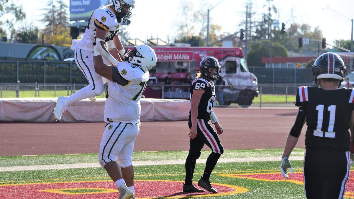 Le Grand High lineman Fermin Villegas (75) lifts up sophomore receiver Reyes Diaz after Diaz scored a 45-yard touchdown during Le Grand’s 35-12 win over Woodland Christian in the Sac-Joaquin Section Division VII championship game at Hughes Stadium in Sacramento, Calif.
