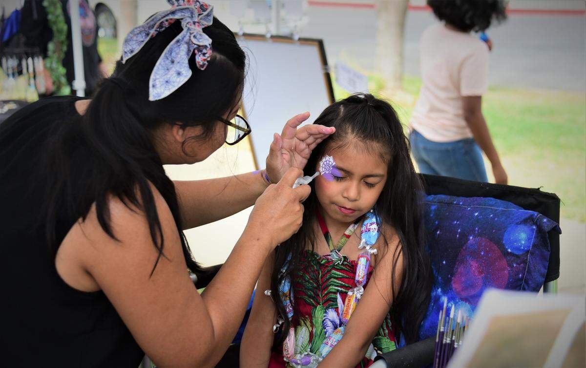 Chanthira Ruaisav of Mariposa paints the face of Irie Chavez, 7, of Merced during the Merced County Nut Festival on Saturday, Oct. 22, 2022 at the Merced County Fairgrounds.