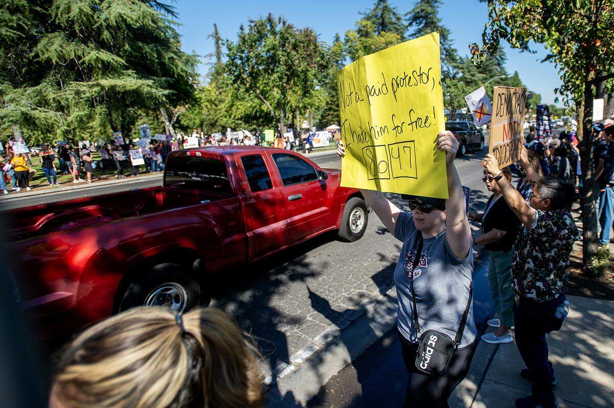 Protesters hold signs while lining M Street during a “No Kings” protest in Merced, Calif., on Saturday, Oct. 18, 2025.
