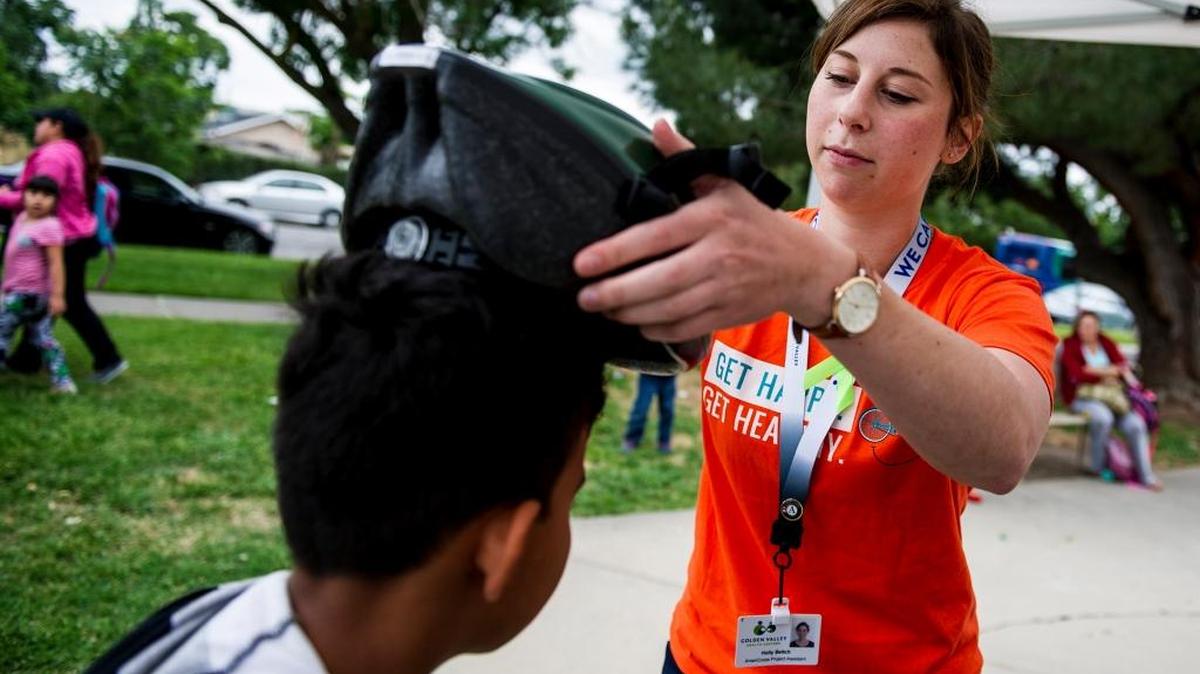 Holly Beitch, 23, of Merced, right, an asthma outreach and education assistant for Golden Valley Health Centers, fits a helmet to the head of Hugo Valdovinos, 9, of Merced, left, during Bike to Work Day as part of National Bike Month in Merced, Calif., on Thursday, May 5, 2016.