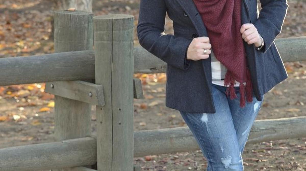 This maroon blanket scarf really pops with the beautiful autumn trees in the background.