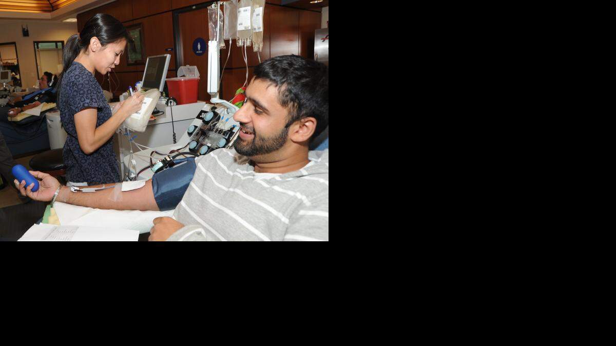 
Amarbir Tahar, 22, of Atwater relaxes with a book as he gives blood in 2012 at the Blood Source Center on East Yosemite Avenue as phlebotomist Shoua Vue monitors his vital signs.
