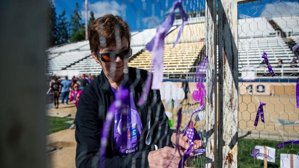 Cancer survivor Sue Umemura, 69, of Canada, ties a ribbon to the prayer wall during the 24-hour Relay for Life event at Don Odishoo Field on the campus of Merced College in Merced, Calif., Saturday, April 23, 2016.