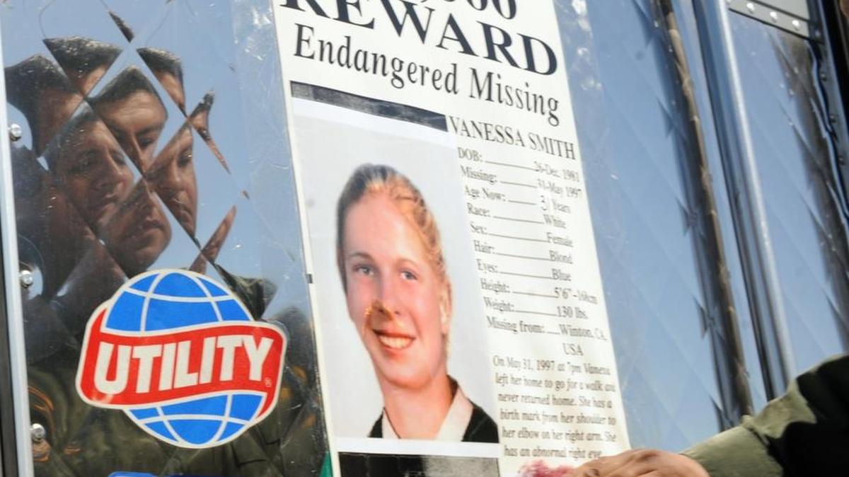 Merced County sheriff’s Detective Roberto Torres is reflected in a truck as he puts a missing poster on the back of it in Livingston in 2013 as part of the effort to find Winton resident Vanessa Smith, who disappeared in 1997 at age 15.