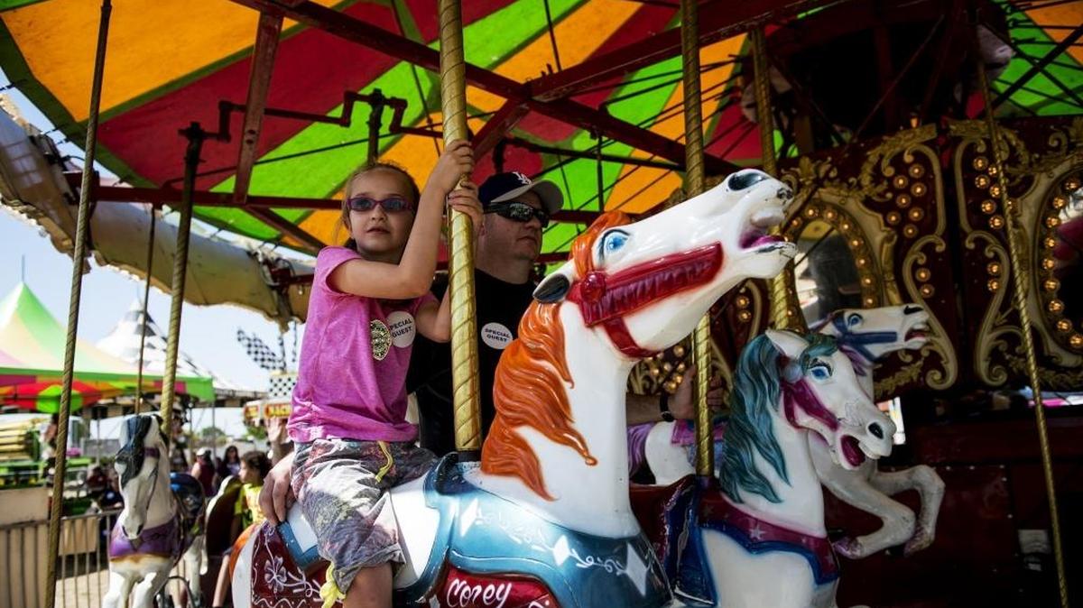 Marissa Allen, 7, of Chowchilla rides the carousel with father Chris, 39, during the Chowchilla-Madera County Fair in Chowchilla, Calif., on Thursday, May 19, 2016.