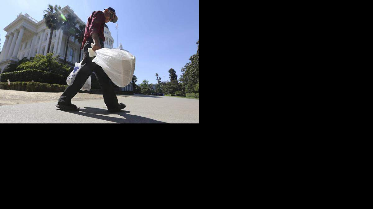 
A man carries plastic single-use bags past the State Capitol in Sacramento in August. Election officials said Monday that a trade group had turned in enough signatures to qualify a referendum on California’s plastic bag ban law, suspending implementation of the nation’s first statewide ban until voters weigh in on the November 2016 ballot. 
