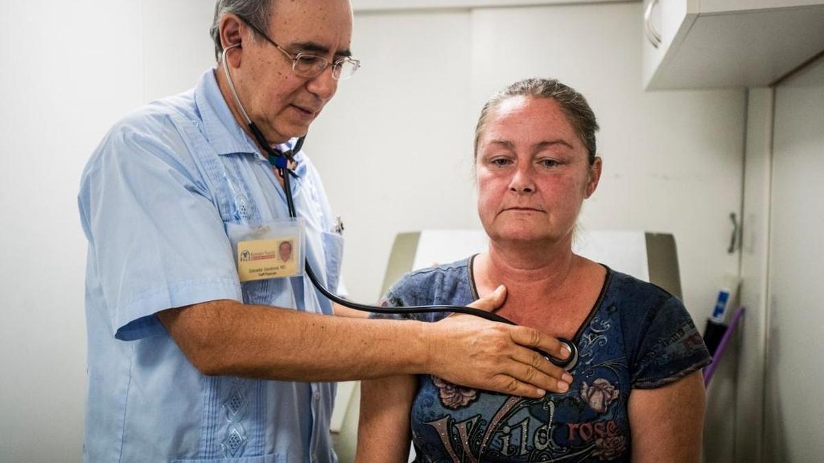 Dr. Salvador Sandoval listens to the breathing of patient Deretha Jones, 46, of Merced at the Golden Valley Centers’ mobile health clinic outside the East 15th Street homeless shelter in Merced, Calif., last year.