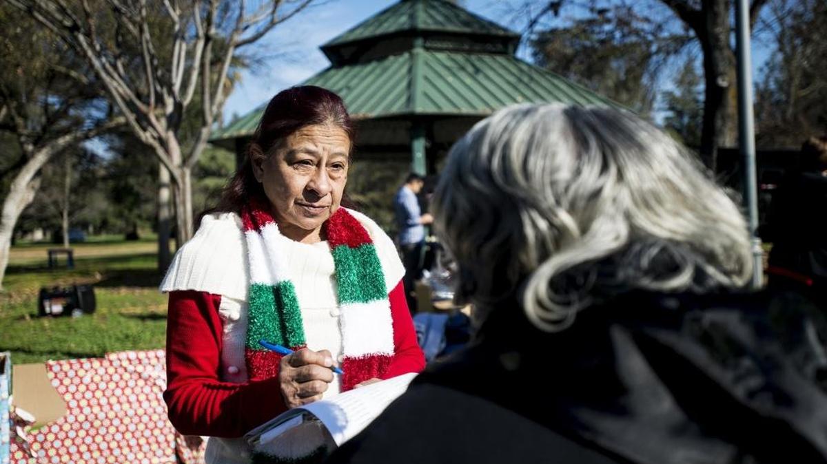 Monica K. Villa, 61, of Merced adds the names of homeless people who have died to a list that was read aloud Wednesday in their memory at Applegate Park in Merced. Food and clothing were available during the service.